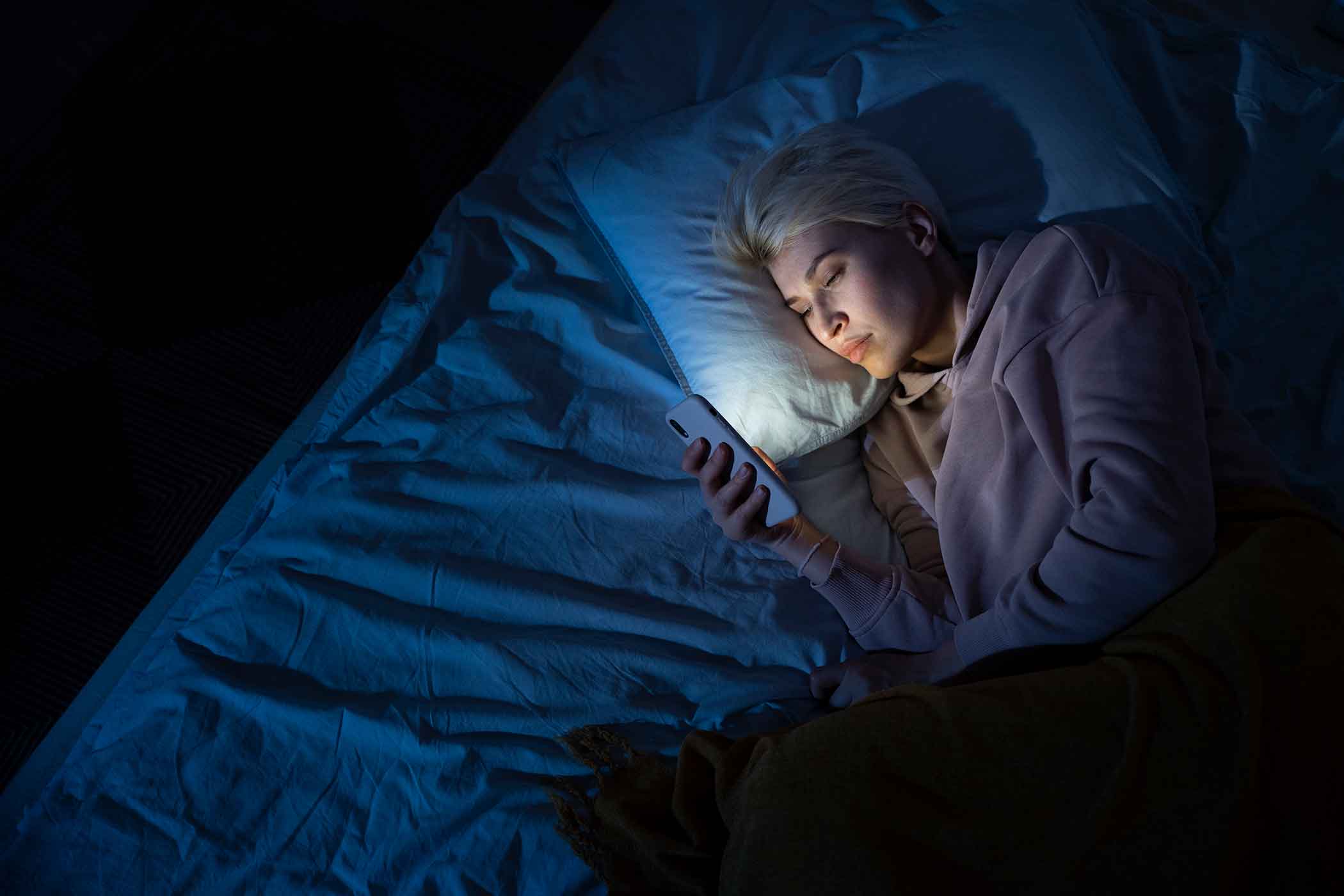 Ležanje u krevetu s mobitelom u ruci